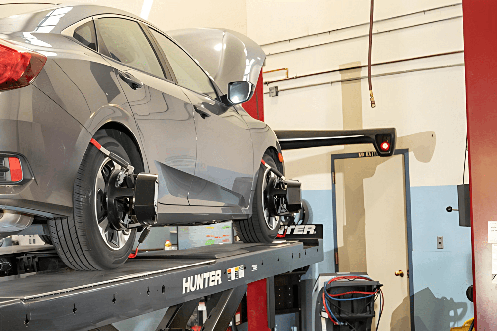 Hunter wheel alignment in Englewood, CO by Autovisions. Image of a gray sedan on a Hunter alignment rack with sensors attached to all four wheels during a precision alignment service.