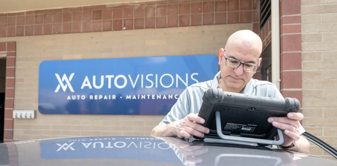 Vehicle inspection in Englewood, CO by Autovisions. Image of a technician using a digital diagnostic tablet outside the shop, highlighting thorough inspections and advanced diagnostic technology for accurate auto repair and maintenance services.