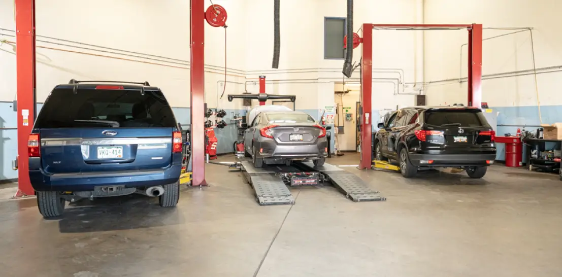 Vehicle maintenance in Englewood, CO by Autovisions. Image of multiple vehicles, including SUVs and sedans, on lifts in a clean service bay for scheduled auto repair and inspections.
