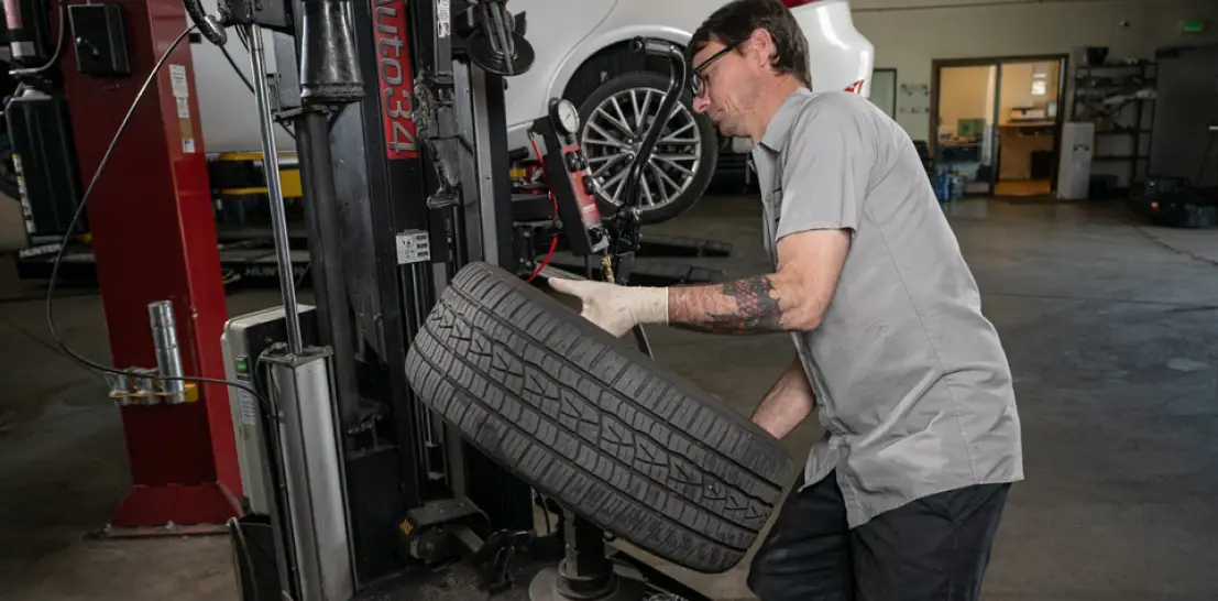 Tire services in Englewood, CO by Autovisions. Image of a mechanic using a tire mounting machine to remove or install a tire, showcasing professional tire repair and maintenance services.